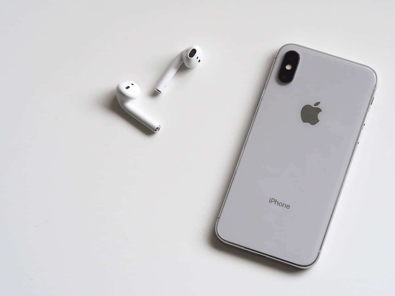 iPhone en AirPods liggen omgekeerd anoniem op tafel