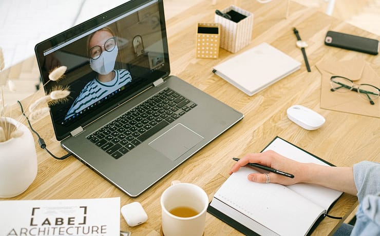 Videobellen in corona tijd vrouw met mondkapje op MacBook